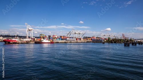 Seattle, Washington, USA - June 4 2021: Cargo container ship and Seattle Logistics shipping terminals waterway. View from Elliott Bay during summer.