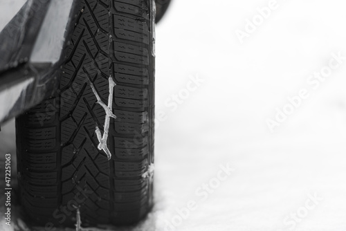 Melting snow in tread pattern of winter tire on car with snow and free space in background