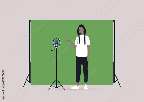 A young female African blogger recording a video with a tripod, a mobile phone, and a chroma key screen