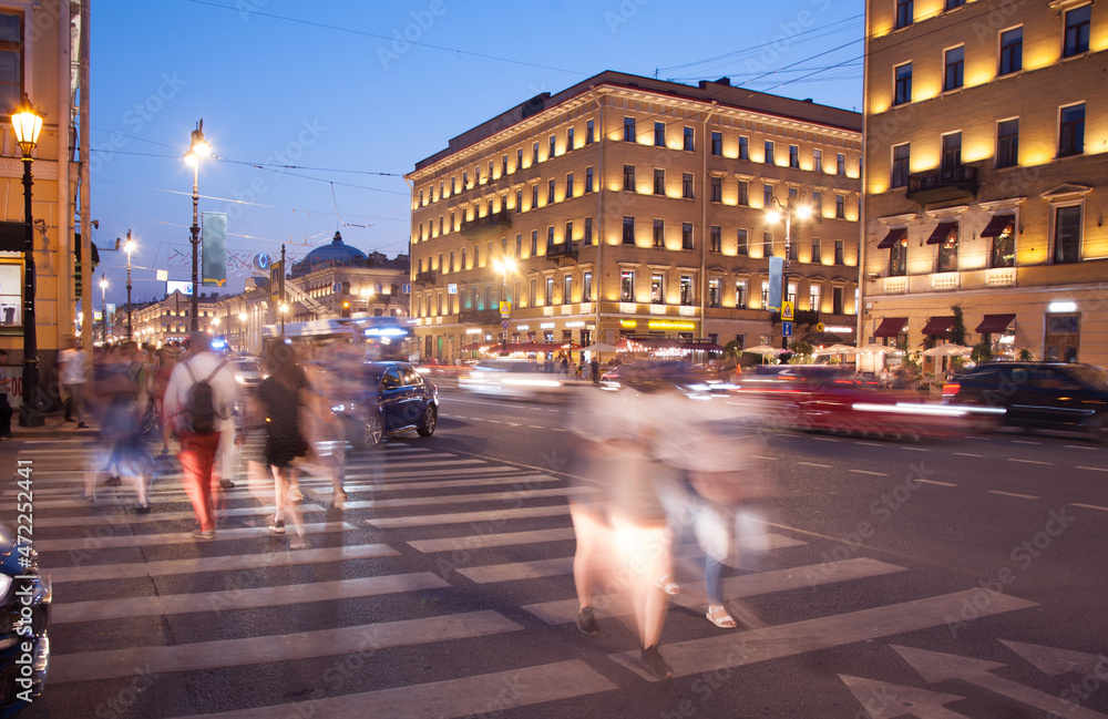 evening city street, cars and people are blurred in motion, long exposure