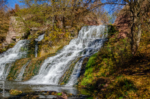 Side view of the waterfall. Landscape on  background of blue sky.