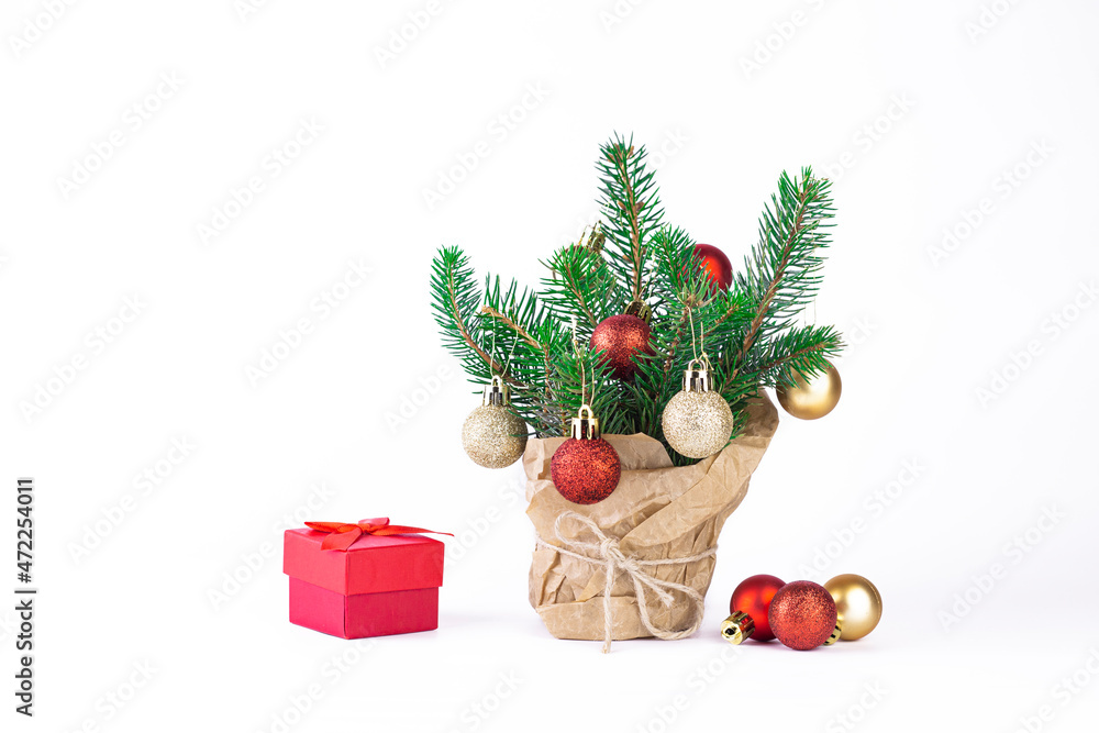 Small Christmas tree in a pot wrapped in craft paper with Christmas tree balls and gift box on white isolated background. little fir tree on white with copy space. Small Christmas tree in a pot wrapped in craft paper with Christmas tree balls and gift box on white isolated background. little fir tree on white with copy space.
