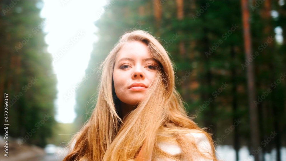 Obraz premium Beautiful woman with a magnificent golden hair. Fun happy young girl shake her head to make hair flying. Attractive young lady turns around and looks into the camera