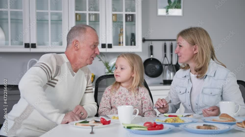 united family, loving parents together with their adorable daughter have fun at lunch sitting at table in kitchen united family, loving parents together with their adorable daughter have fun at lunch sitting at table in kitchen
