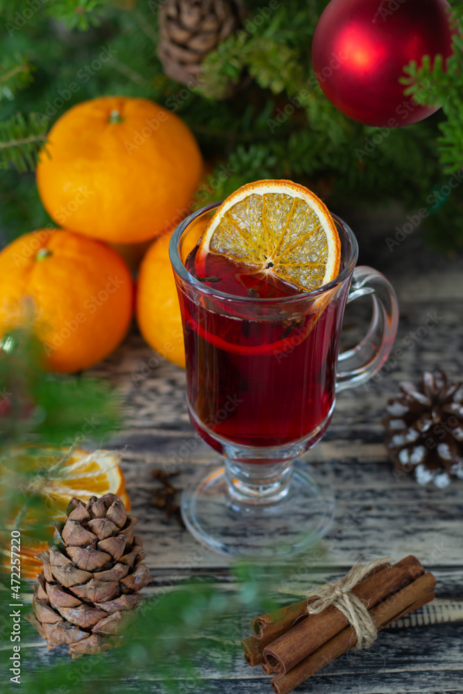 A warming glass of mulled wine adorned with an orange slice, set beside fresh oranges, festive baubles, and aromatic cinnamon sticks on a rustic table. A warming glass of mulled wine adorned with an orange slice, set beside fresh oranges, festive baubles, and aromatic cinnamon sticks on a rustic table.