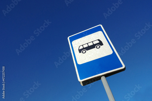 Bus stop sign on blue sky background close-up