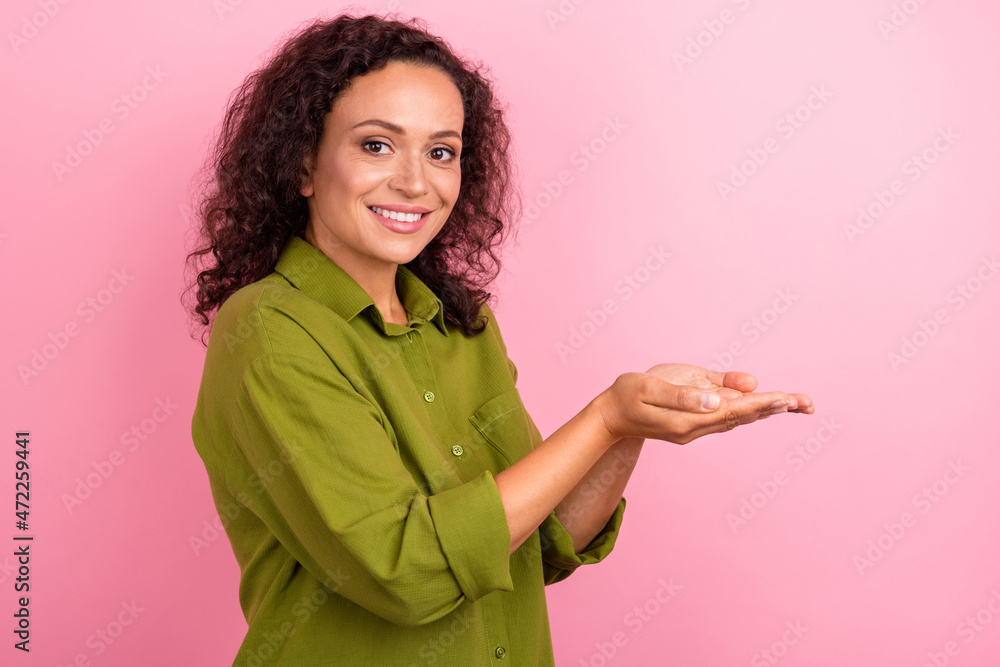 Photo of young cheerful happy afro american woman hold hands empty space object smile isolated on pink color background Photo of young cheerful happy afro american woman hold hands empty space object smile isolated on pink color background