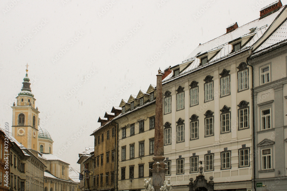 Facciate e tetti innevati di Mestni trg Lubiana con scorcio della fontana dei fiumi carniolani Facciate e tetti innevati di Mestni trg Lubiana con scorcio della fontana dei fiumi carniolani