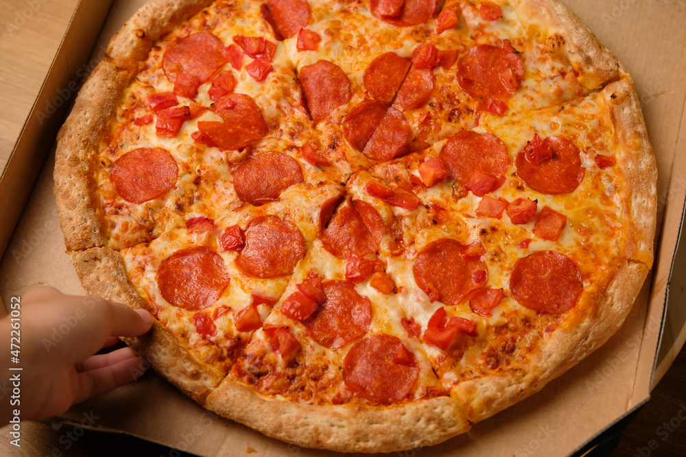 Fresh pepperoni pizza in a box with salami slices delivered home. Fast food delivery from restaurant.
