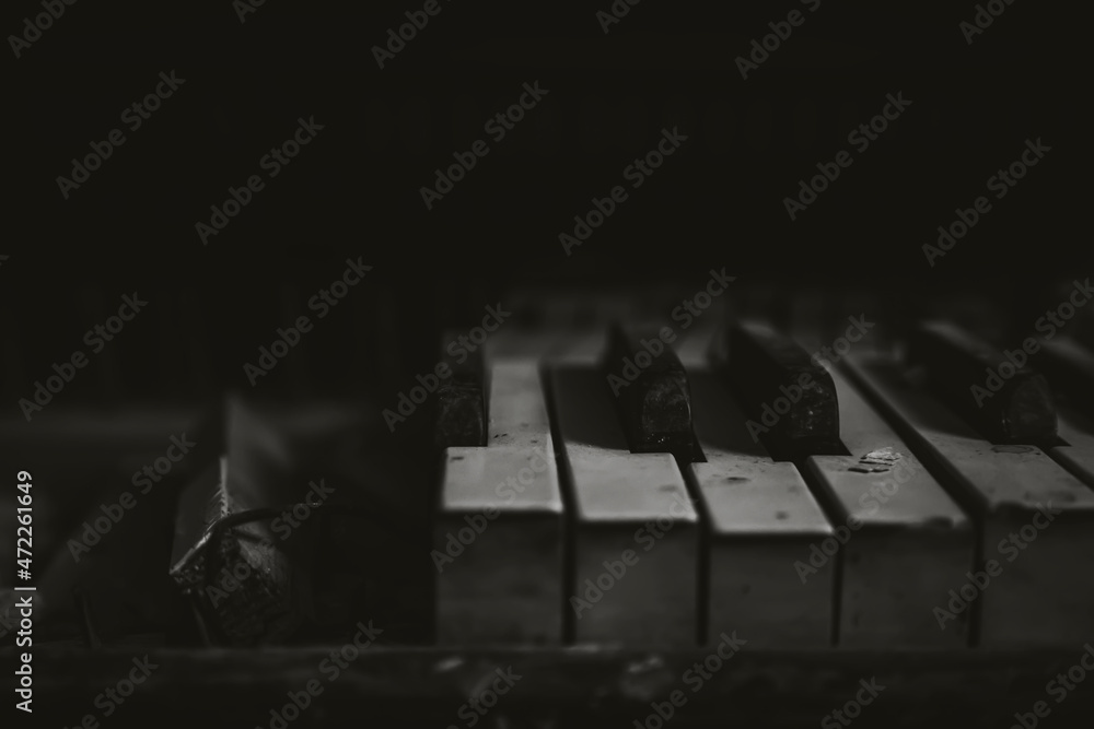 Black and white dirty keys of an abandoned piano. An old musical instrument. Play of light and shadow. Forgotten piano.