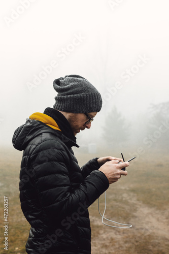 A guy stands in a foggy forest with a drone control panel in his hands. He flies a quadcopter.