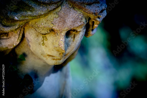 Sad ngel with tears in the eyes. Fragment of an antique statue. Death concept. Copy space.