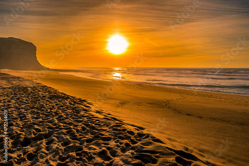 Footprints in the sand with colorful sunset on the beach at Foz do Sizandro, São Pedro da Cadeira PORTUGAL photo