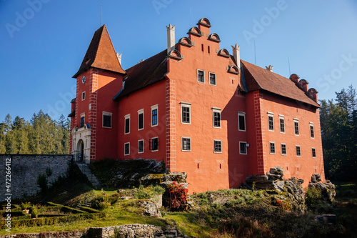 Cervena Lhota, South Bohemia, Czech Republic, 9 October 2021: Beautiful small romantic red water chateau, Antique castle with fall color at sunny autumn day, stone bridge and entrance gate