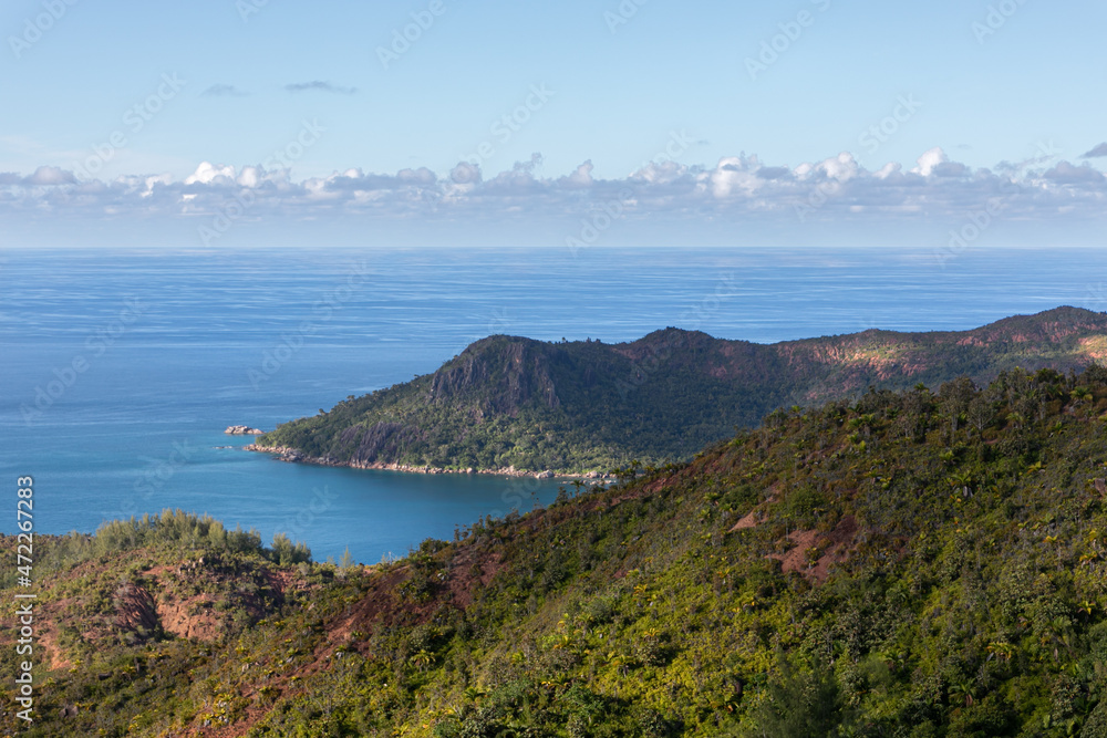 Panoramic photo from the Zimbabwe viewing point (Grand fond) at Praslin island of Seychelles. Endless oceanic landscape with rugged shoreline, sandy, rocky beaches and hills covered with jungle
