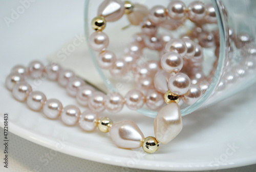 Wedding decor: a string of pink pearls in a glass on a white plate