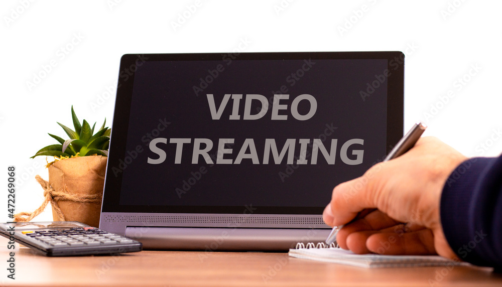 Video streaming symbol. Tablet with concept words Video streaming. Businessman hand with pen, house plant. Copy space. Beautiful white background. Business, video streaming concept, copy space. Video streaming symbol. Tablet with concept words Video streaming. Businessman hand with pen, house plant. Copy space. Beautiful white background. Business, video streaming concept, copy space.