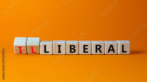 Illiberal or liberal symbol. Turned wooden cubes and changed the word illiberal to liberal. Beautiful orange background. Business, political and illiberal or liberal concept. Copy space. photo