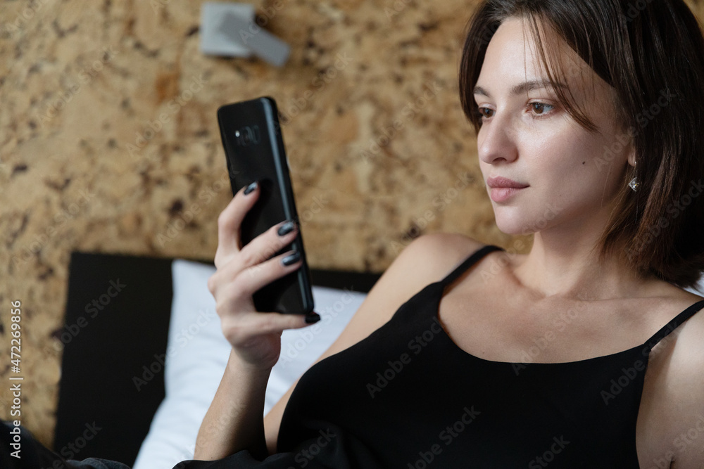 Young brunette woman looking at phone at home Young brunette woman looking at phone at home