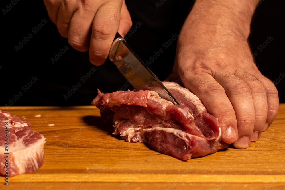 close-up of male hands slicing meat.