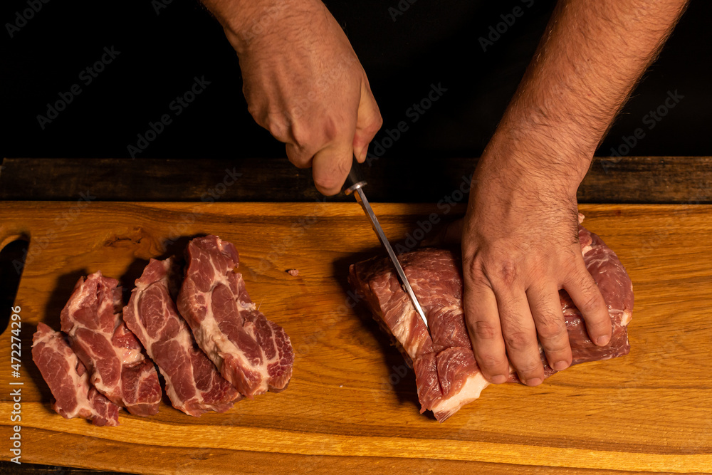 close-up of male hands slicing meat.