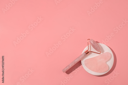 Gua Sha massage tools on pink background. Quartz roller, facial massage and relaxation. Anti age and lifting at home. Free space for text, copy space. Beauty background.