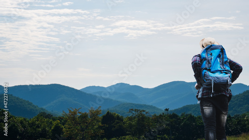 African man traveler views landscape of mountains with evergreens and deep blue sky