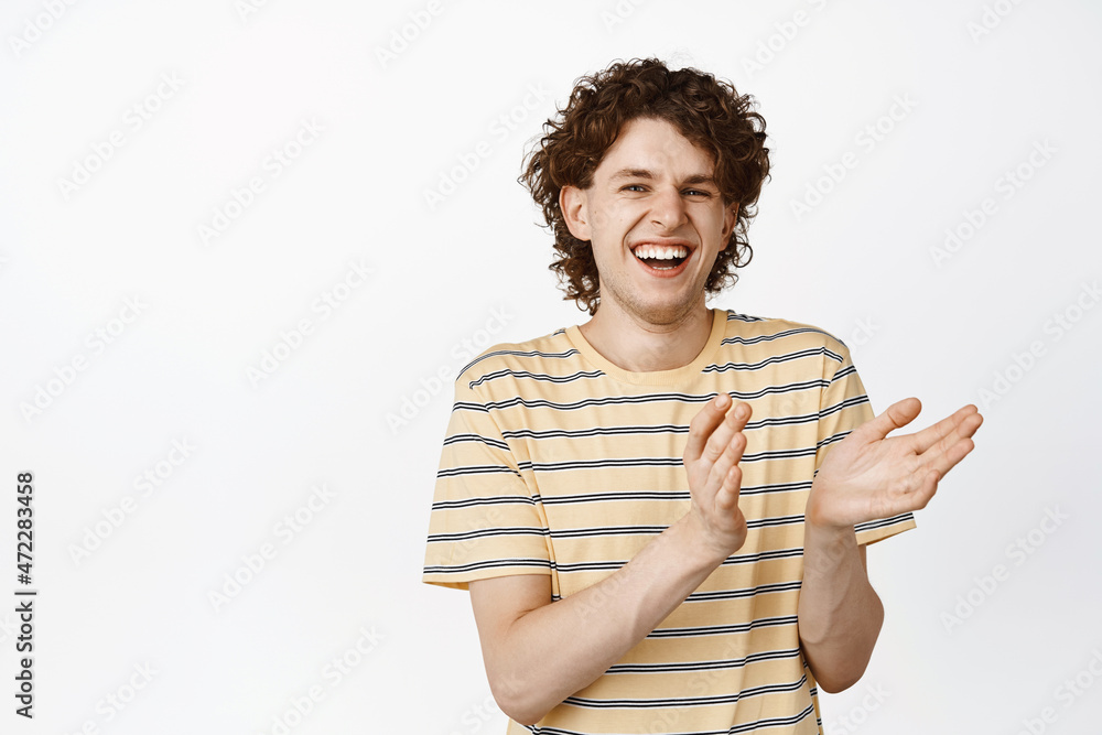 Happy charismatic guy laughing and applausing, clap hands and smiling at camera, standing over white background Happy charismatic guy laughing and applausing, clap hands and smiling at camera, standing over white background