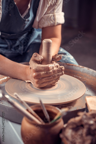 The potter works in the workshop. Hands and a potter's wheel close-up
