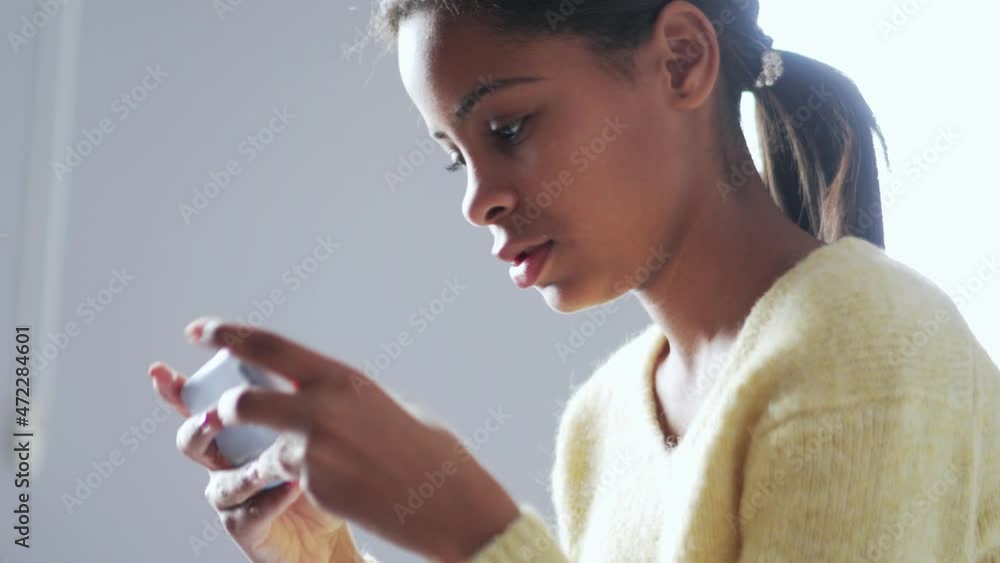 Meditative African girl texting by phone at home Meditative African girl texting by phone at home