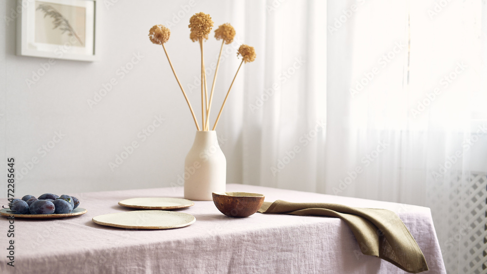 Modern dining table setting. Only natural materials - earthenware, linen textiles, dried flowers. Side view.