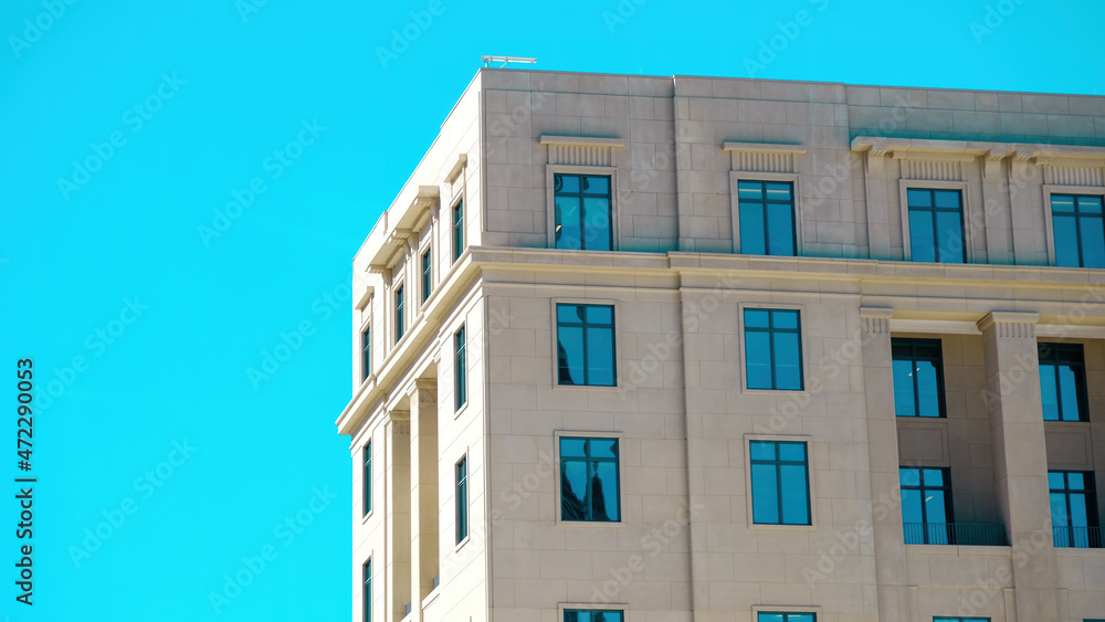 Modern neoclassical building with intense blue sky reflectedin windows and negative space for copy