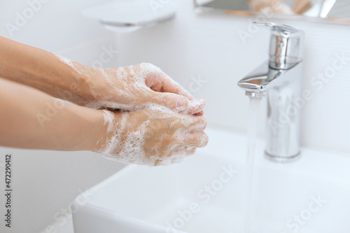 Fototapeta Naklejka Na Ścianę i Meble -  Washing hands under the flowing water tap. Washing hands rubbing with soap for corona virus prevention, hygiene to stop spreading corona virus in or public wash room. Hygiene concept hand detail