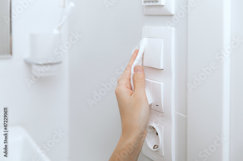 Cleaning switches and sockets with a microfiber cloth. Woman hand using wet wipe for cleaning home room door link. Sanitize surfaces prevention in hospital and public spaces against corona virus