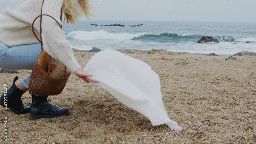 Young woman is spreading picnic blanket on a beach, going to have nice time near ocean, relaxing and getting inspiration from nature, Slow motion. Young woman is spreading picnic blanket on a beach, going to have nice time near ocean, relaxing and getting inspiration from nature, Slow motion.