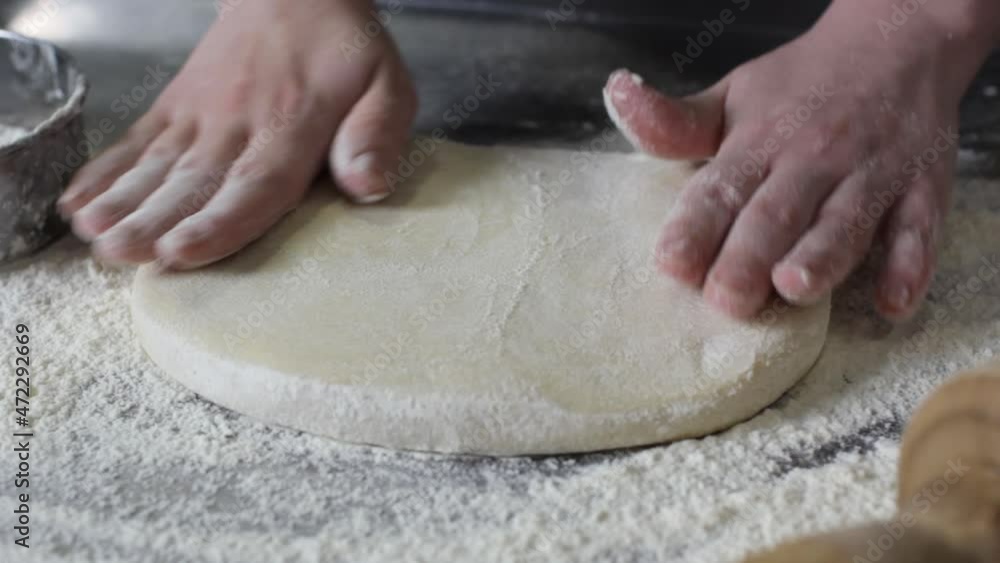 A professional chef stretches and twists soft Italian pizza dough with his hands. close-up A professional chef stretches and twists soft Italian pizza dough with his hands. close-up