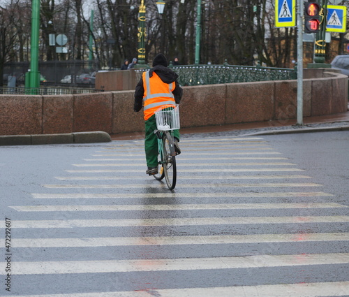 A worker in an orange vest on a bicycle violates traffic rules, Moika River embankment, St. Petersburg, Russia, November 2021 © Станислав Вершинин