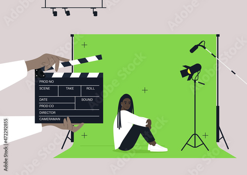 A young female African character starring in a drama, a movie set with a chroma key screen, lighting equipment, microphones, and a clapper board