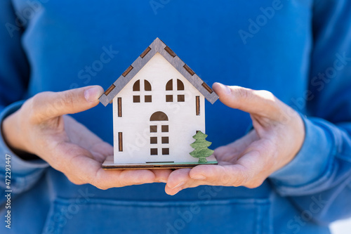 a woman's hand holds a mock-up or miniature of a residential building. purchase and sale of real estate, construction of a residential building. monolith or frame of an apartment building, engineering