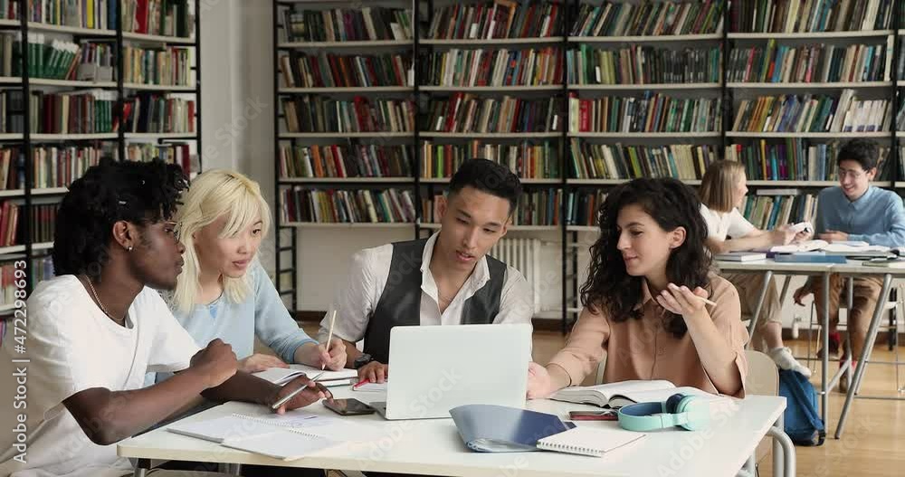 Group of schoolmates, attractive highschool multinational students sit at desk in library with laptop writing essay or summary, take notes busy in exam preparation using modern tech. Education concept Group of schoolmates, attractive highschool multinational students sit at desk in library with laptop writing essay or summary, take notes busy in exam preparation using modern tech. Education concept
