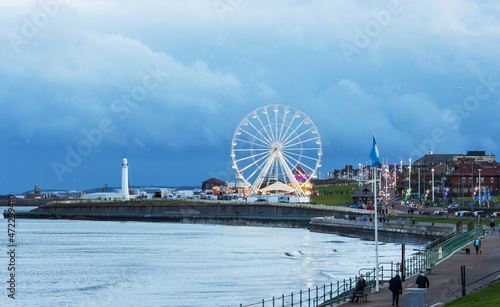 Dramatic sky over Seaburn Bay with ferris wheel and lighthouse.