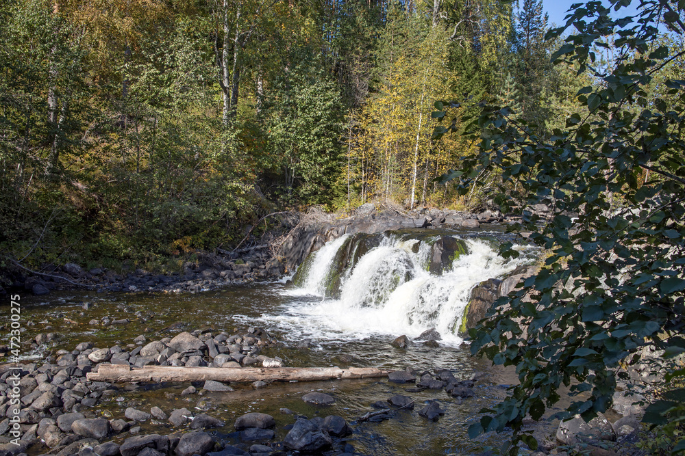Autumn landscape with a waterfall on the Oster river in Karelia. The forest borders the shores Autumn landscape with a waterfall on the Oster river in Karelia. The forest borders the shores