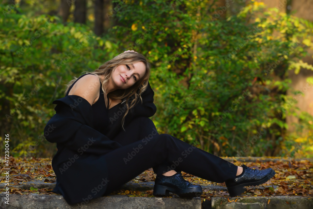 Portrait of a young beautiful girl with curly hair on a background of an autumn forest Portrait of a young beautiful girl with curly hair on a background of an autumn forest