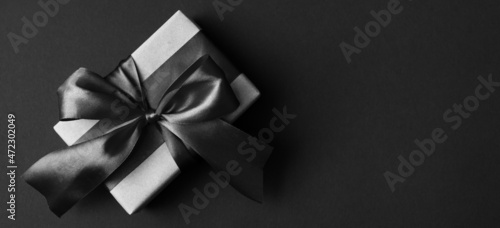 Banner made of Present box with black bow on black background. Black friday sale concept. Minimal style. Flat lay, top view, copy space.