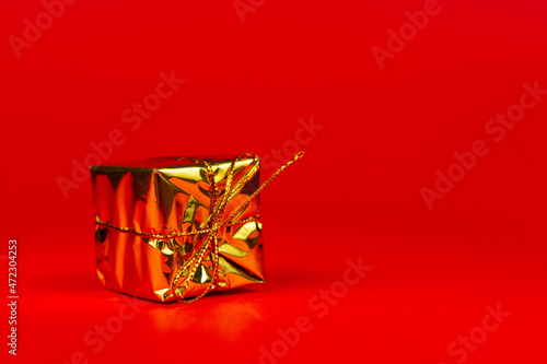 złoty zapakowany prezent na czerwonym tle.