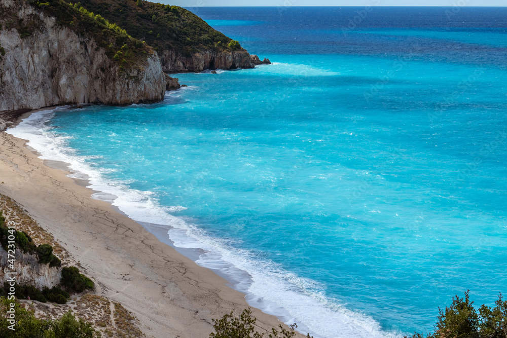 Aerial view on Mylos sandy beach with azure vibrant stormy waves on coast of Lefkada island in Greece. Summer nature vacation travel to Ionian Sea