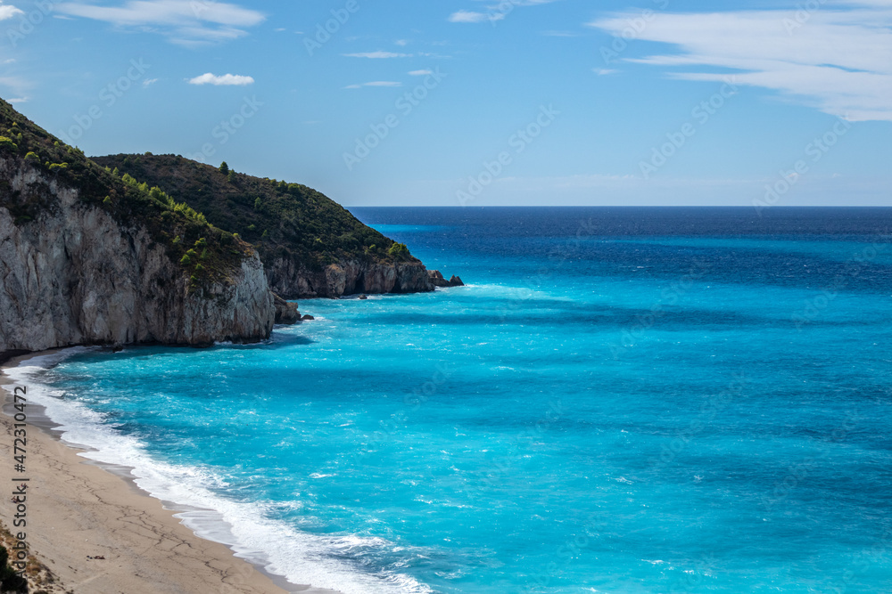 Azure vibrant waves on coast of Lefkada island. Mylos sandy beach in Greece. Summer nature vacation travel to Ionian Sea