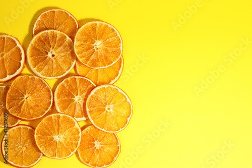 Dried slices of orange fruit on yellow paper background.