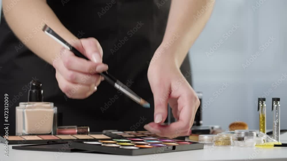 Palette of shadows on white table. Visagiste professional set, beauty industry concept. Trying makeup products using brush, colorful eyeshadows. Foundation and lipsticks on background. Palette of shadows on white table. Visagiste professional set, beauty industry concept. Trying makeup products using brush, colorful eyeshadows. Foundation and lipsticks on background.