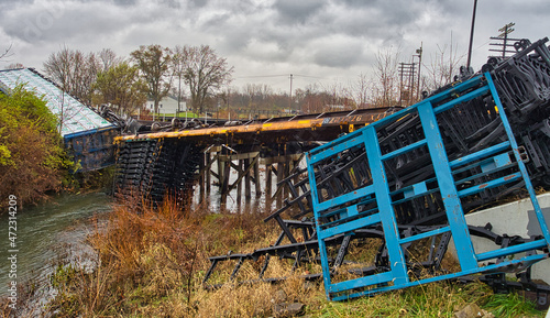 Photos Train derailment over a small bridge on a rainy day.